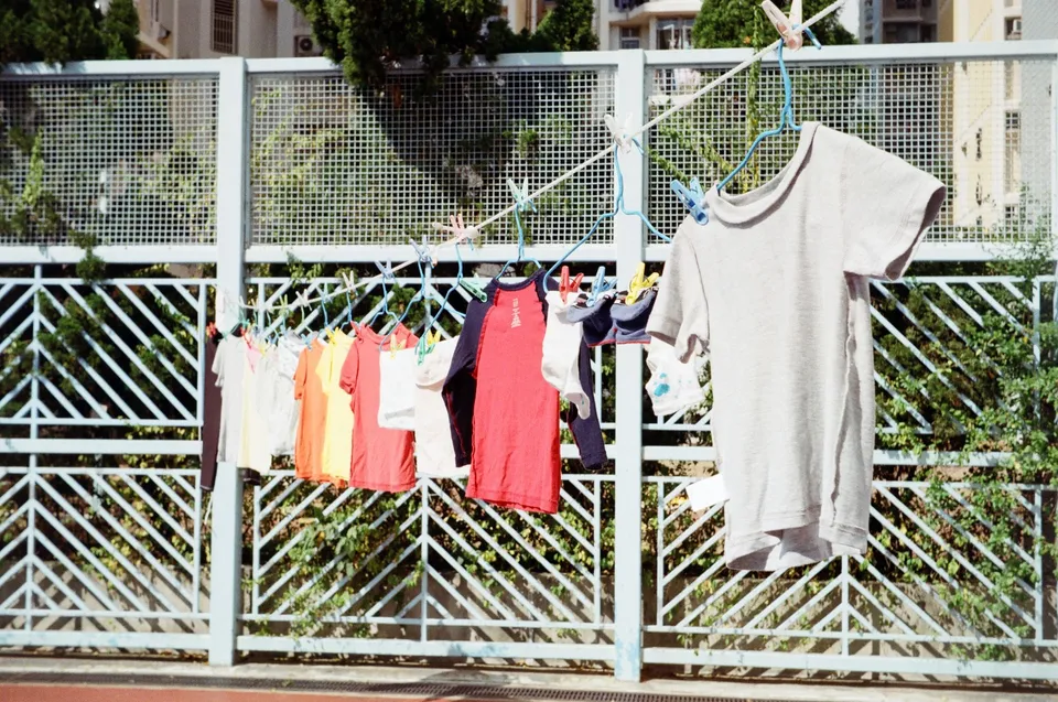 a clothes line with clothes hanging on a clothes line next to a fence and trees in the background