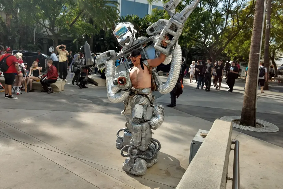 a man in a robot suit holding a giant metal object in his hands